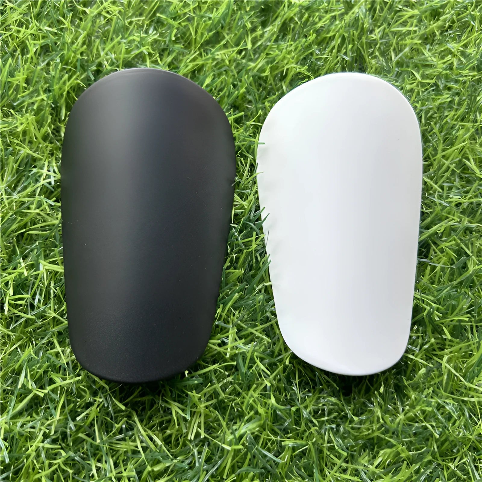 Pair of extra small black plastic football shin guards for junior players.