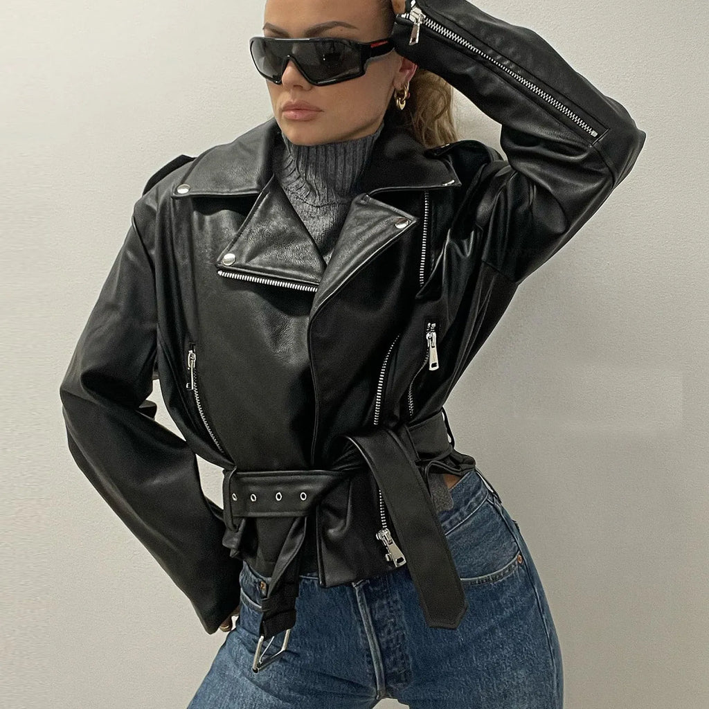 Black punk style leather jacket with a Peter Pan collar and regular sleeves on a hanger.