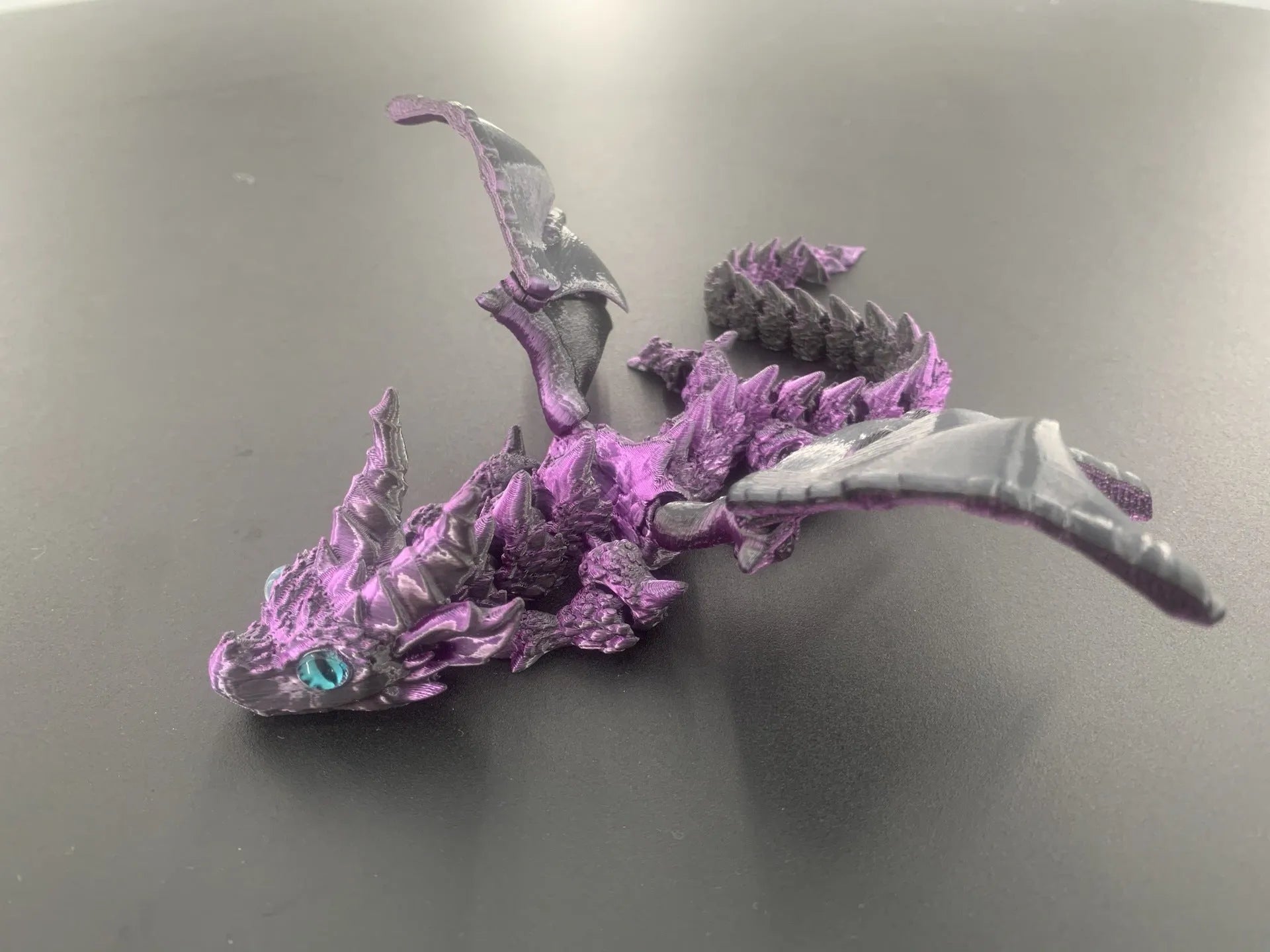3D printed red and gold flying dragon wings decoration toy on a white background.