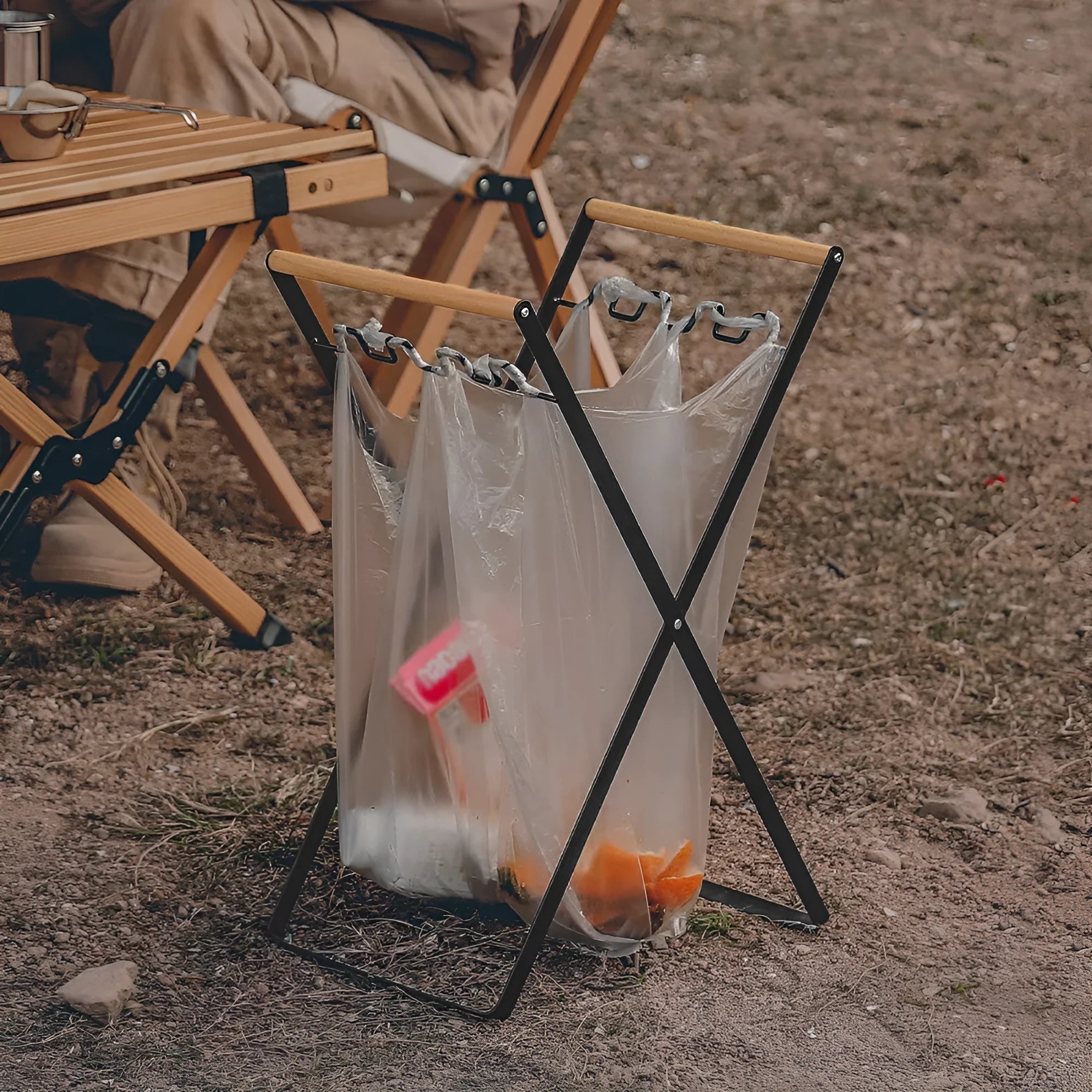 Black folding outdoor trash rack with wooden handle standing on a patio.