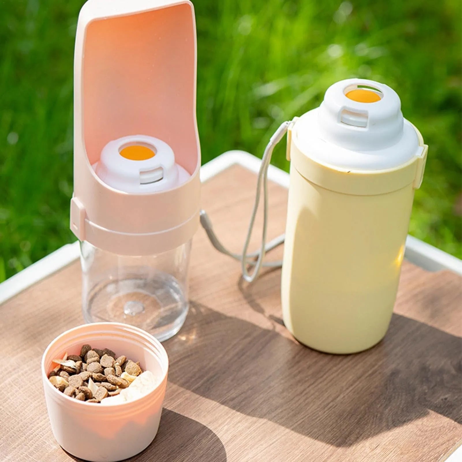 Green portable dog water bottle and feeder with attached lanyard, showing separate food and water compartments.