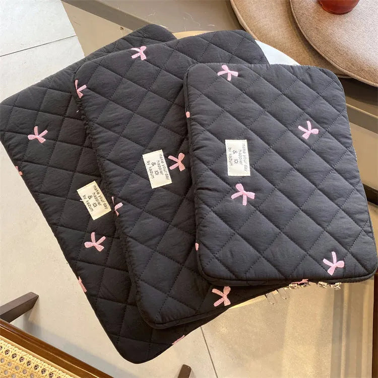 White nylon laptop bag with embroidered rhombus pattern and fabric bow, shown alongside black, light blue, and light pink colour options.