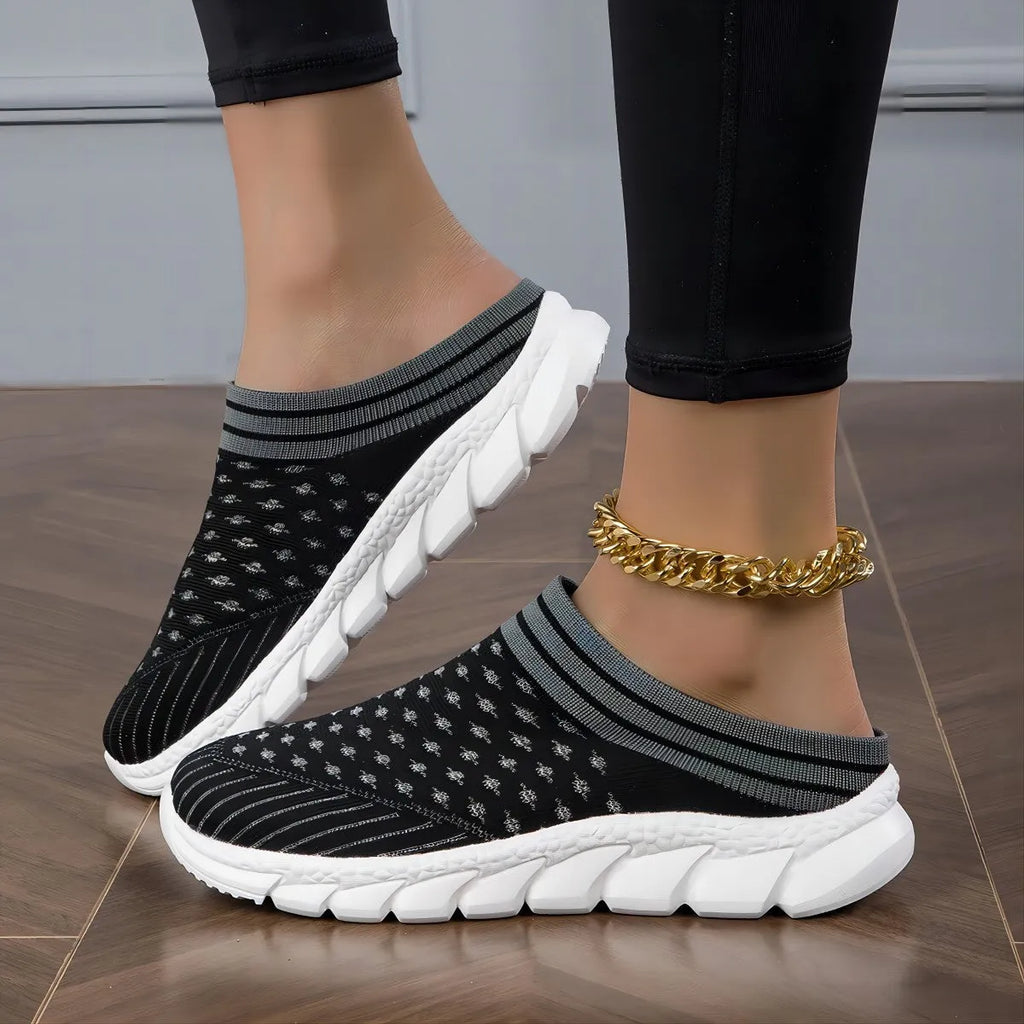 Black women's Flyknit sports slipper with hollowed-out pattern and striped design on a light background.