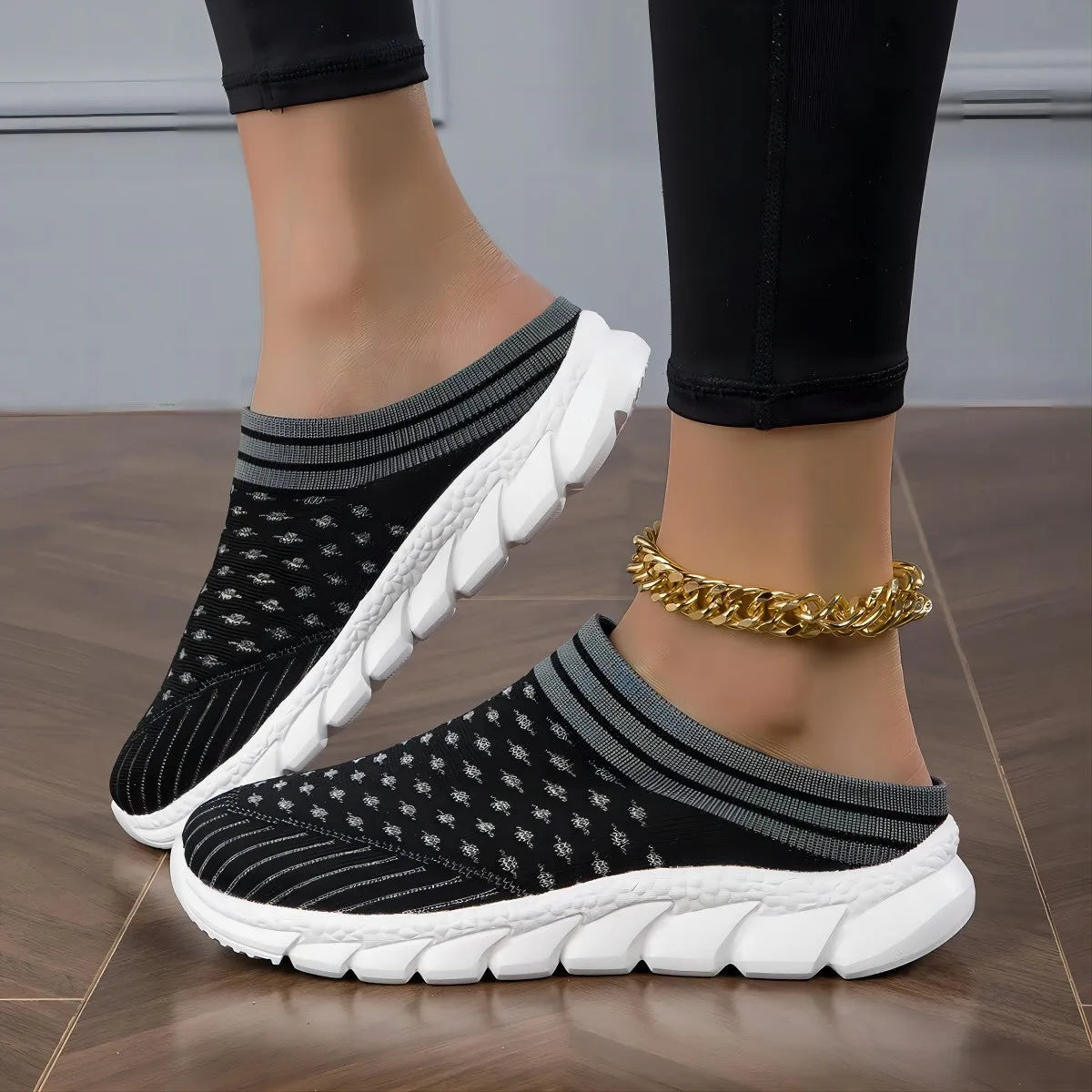 Black women's Flyknit sports slipper with hollowed-out pattern and striped design on a light background.