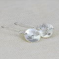 Silver round women's earrings with glossy finish showing bird and floral retro design details