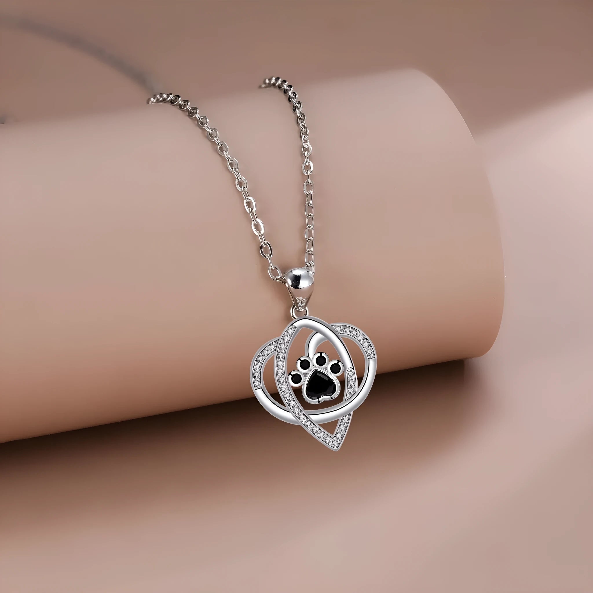 Close-up of a dog's paw print copper pendant necklace on a cross chain.
