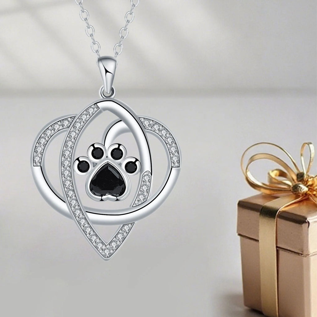 Close-up of a dog's paw print copper pendant necklace on a cross chain.