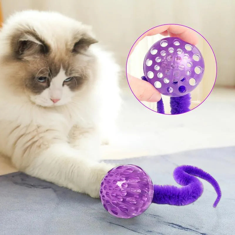 Green bouncy ball cat toy with plush tail on wooden floor
