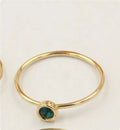 Women's 14K gilded copper knuckle ring with zircon accents in green, shown on a model's finger.