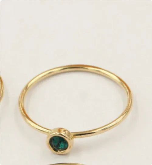 Women's 14K gilded copper knuckle ring with zircon accents in green, shown on a model's finger.