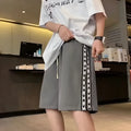 Men's black loose-fit polyester track pants with an elasticated waist, shown in a casual setting.