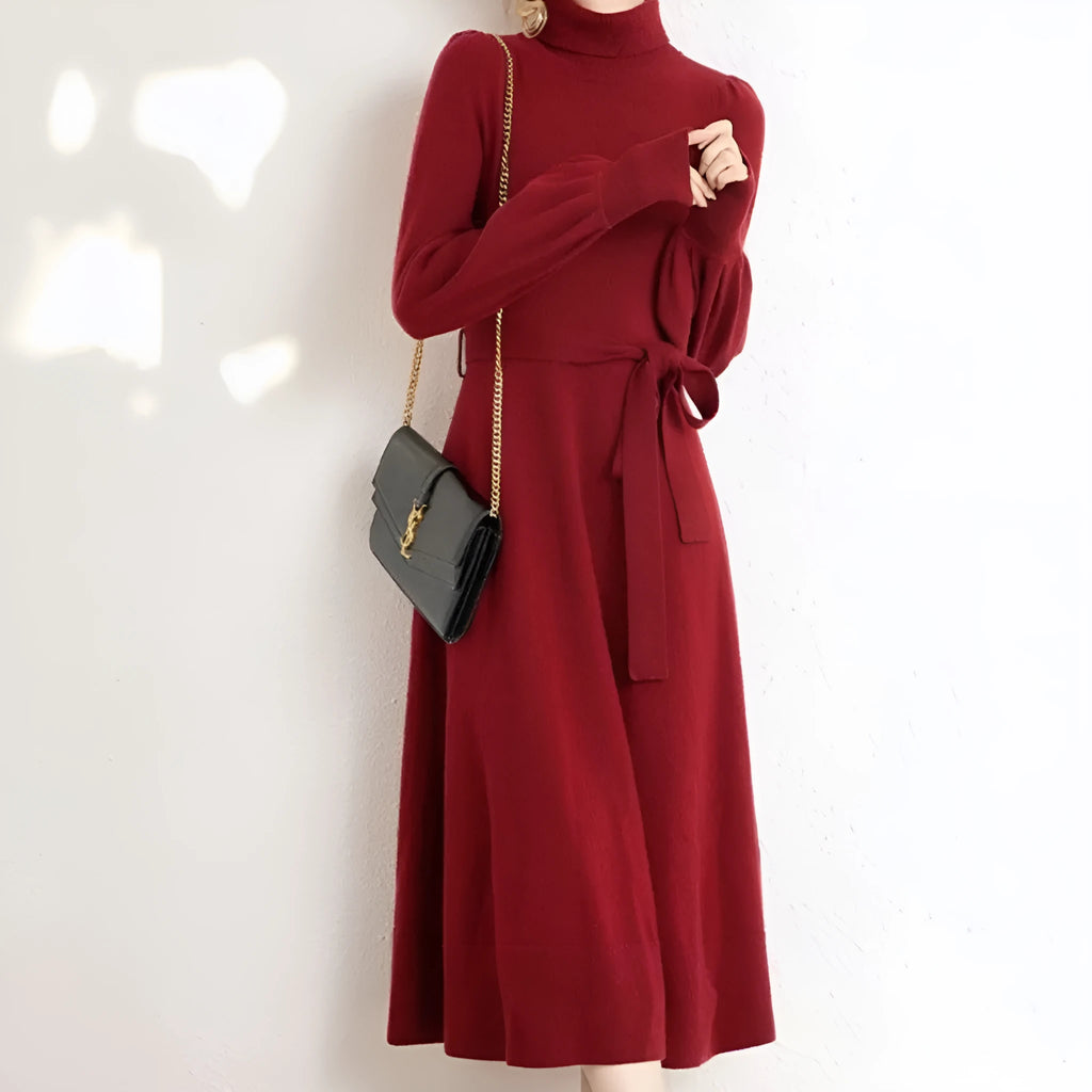A woman wearing a rose red turtleneck knit dress with long sleeves, an elastic waist, and a loose mid-length hem.
