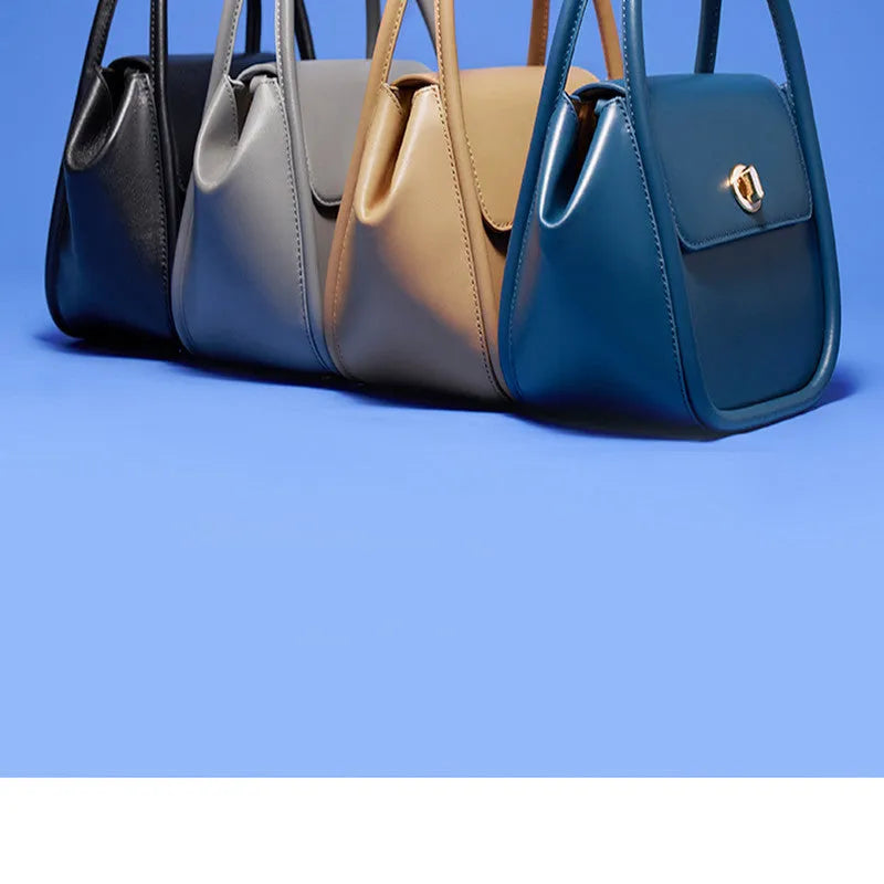 Brown leather wing-shaped tote bag with a buckle detail and latch closure, shown with a single cross-body strap.