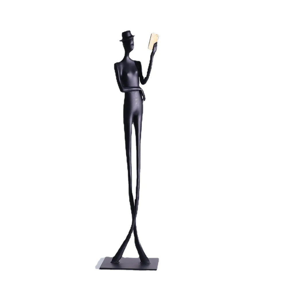 Black cast aluminium sculpture of a woman reading, modern minimalist desk decor.