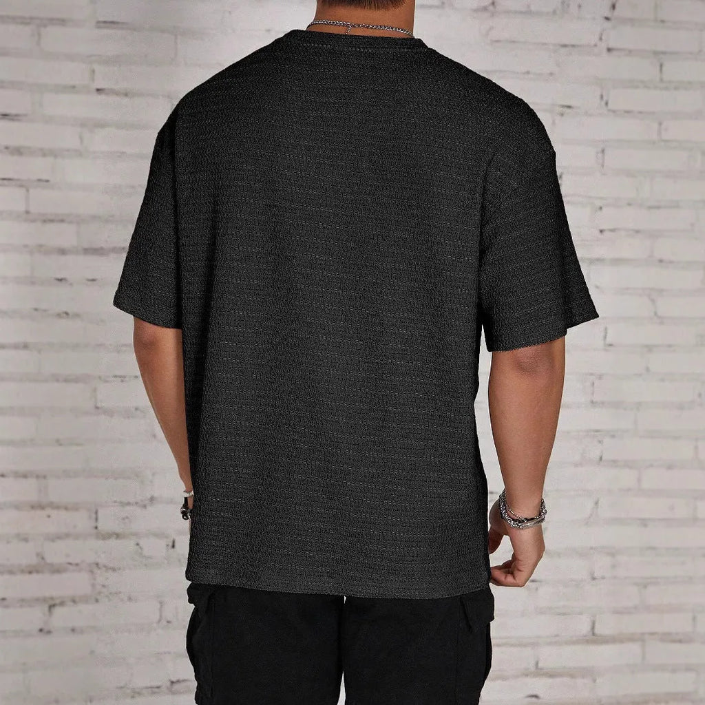 Men's loose slim fit solid colour short sleeve T-shirt in light blue on a grey background.