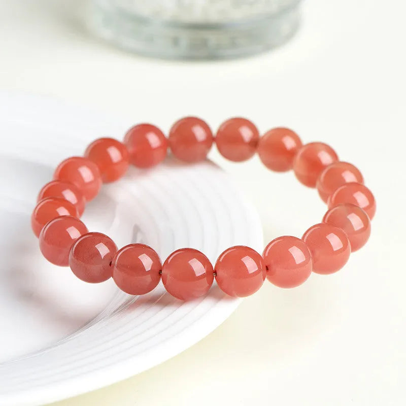 Natural South cherry red agate bracelet showing polished stone beads in scattered arrangement