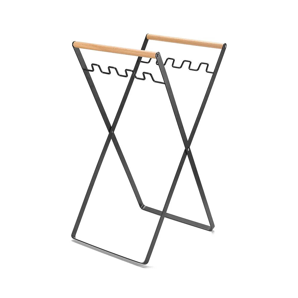 Black folding outdoor trash rack with wooden handle standing on a patio.