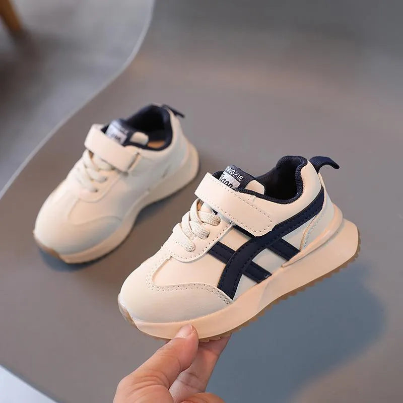 Children's white sneakers with Velcro fastening and rubber sole shown from side view