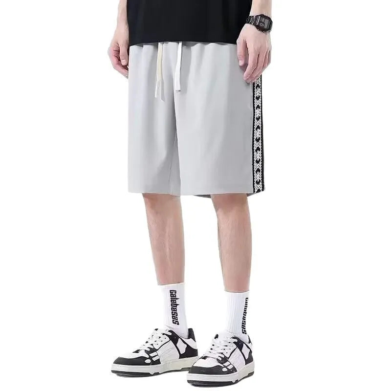 Men's black loose-fit polyester track pants with an elasticated waist, shown in a casual setting.
