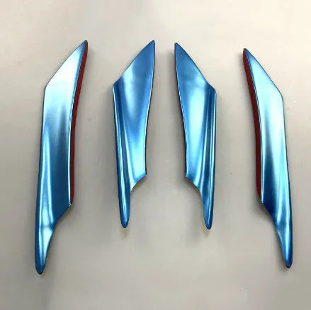 Set of four carbon fibre pattern bumper blade spoilers for car modification on a black background.