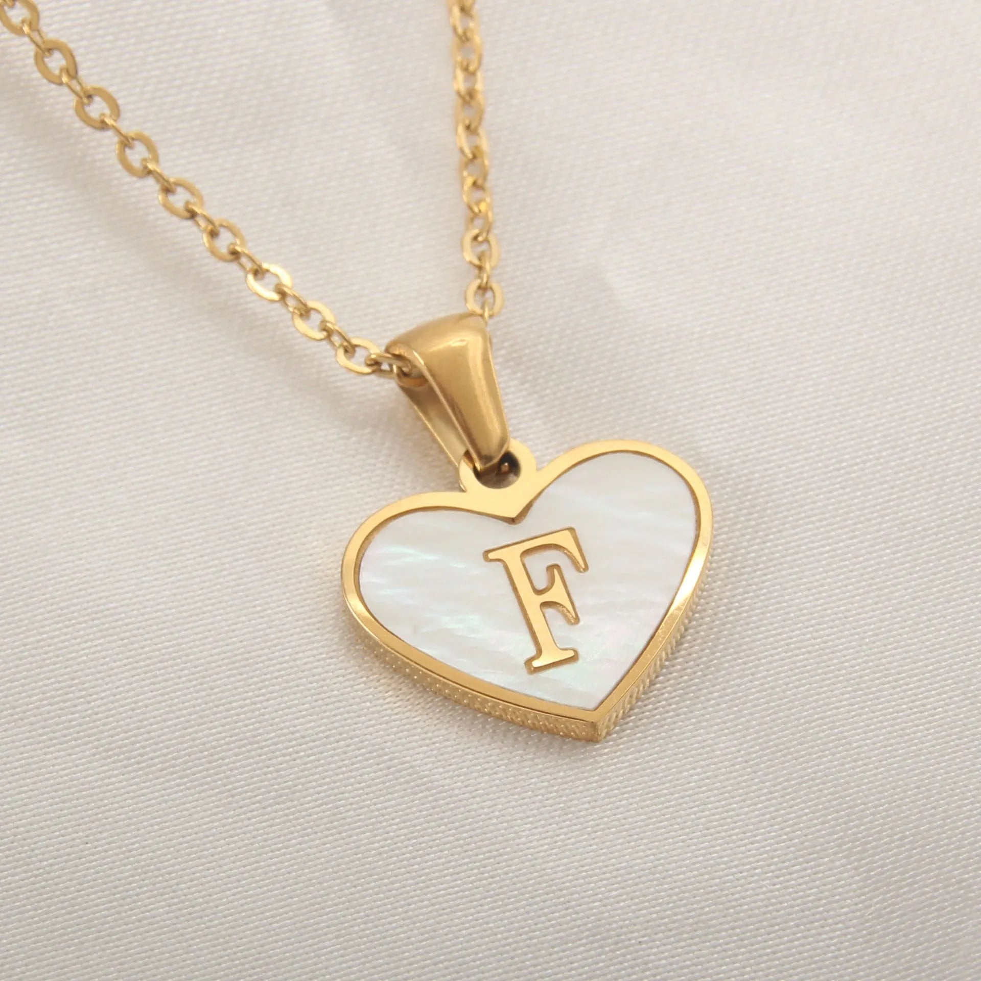 Gold-plated heart necklace with white shell pendant showing initial engraving on stainless steel chain