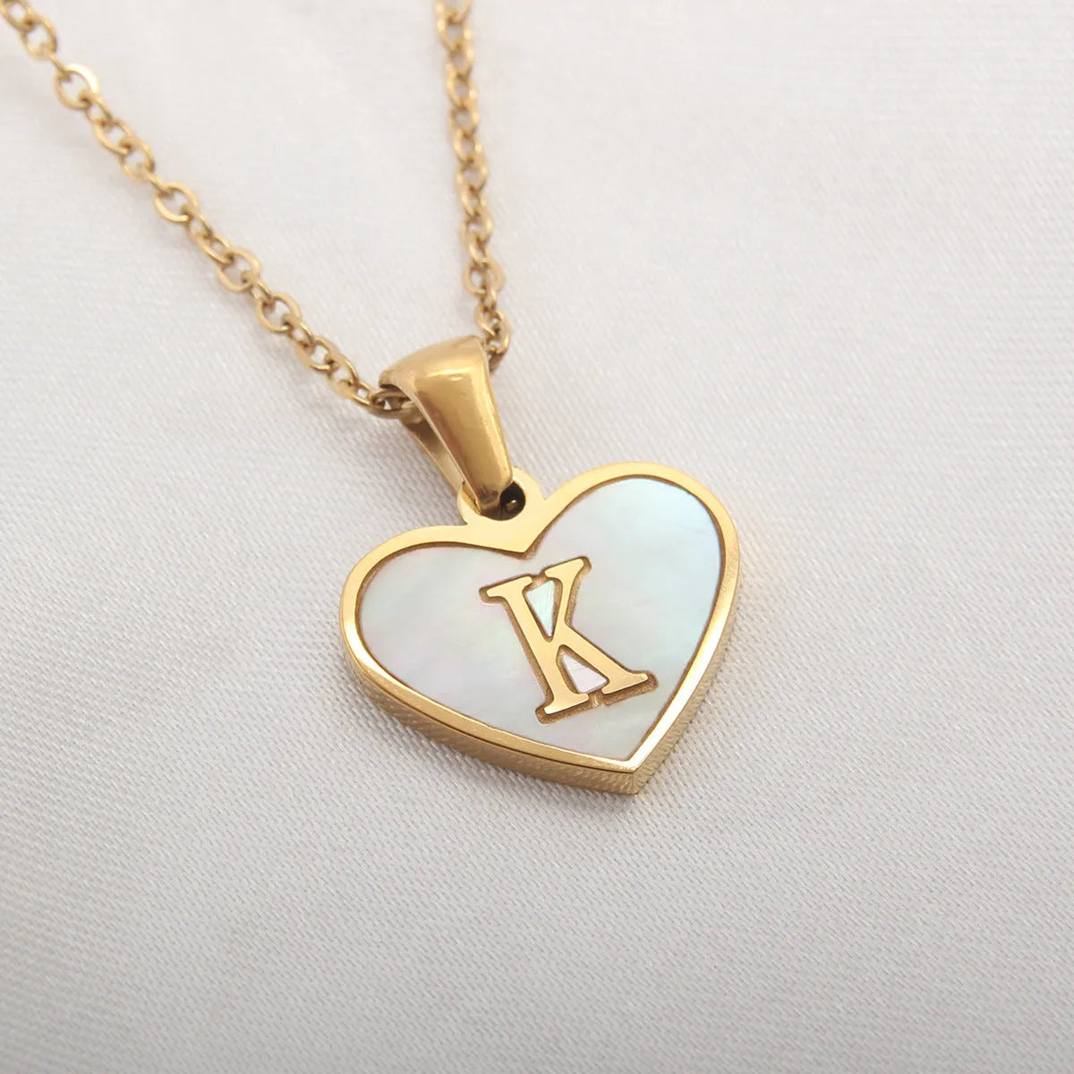 Gold-plated heart necklace with white shell pendant showing initial engraving on stainless steel chain