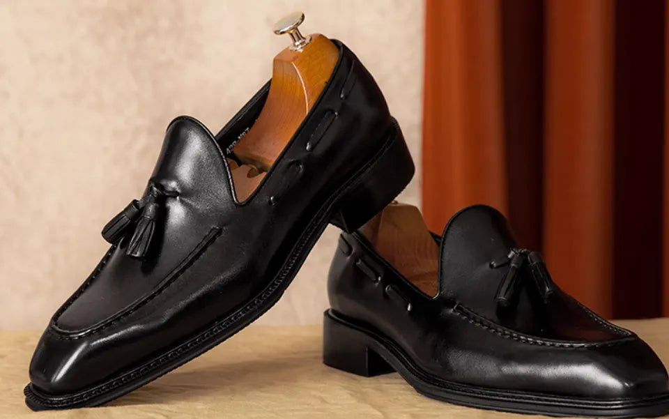 Men's black leather slip-on loafers with fringed detailing and polished finish