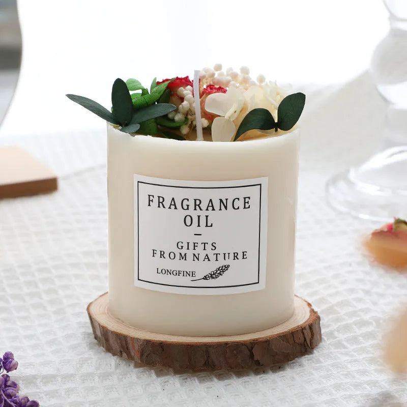 Decorative scented candle with dried flowers inside, shown with wooden chip base and gift box packaging.