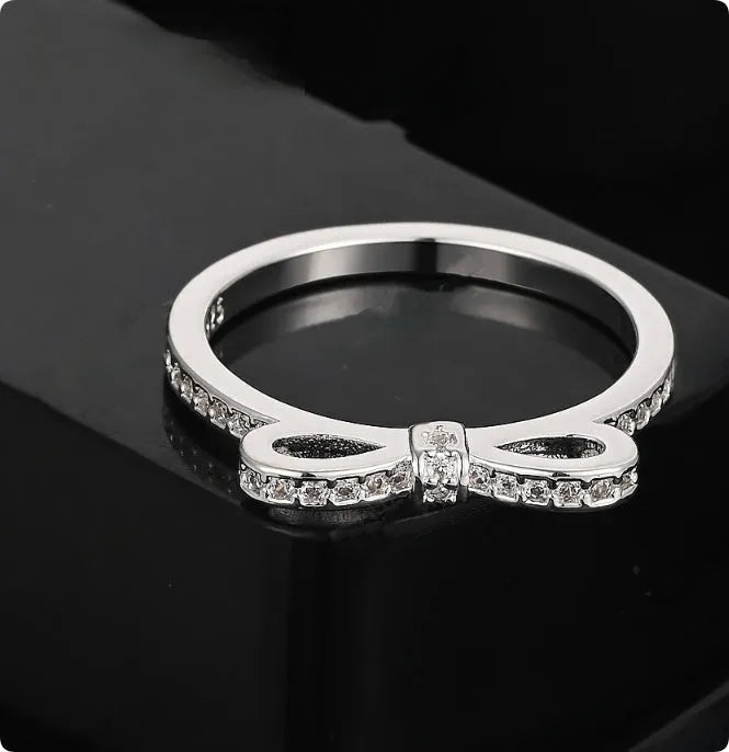Silver couple style ring with bow shape decorated with rhinestone and zircon crystals.