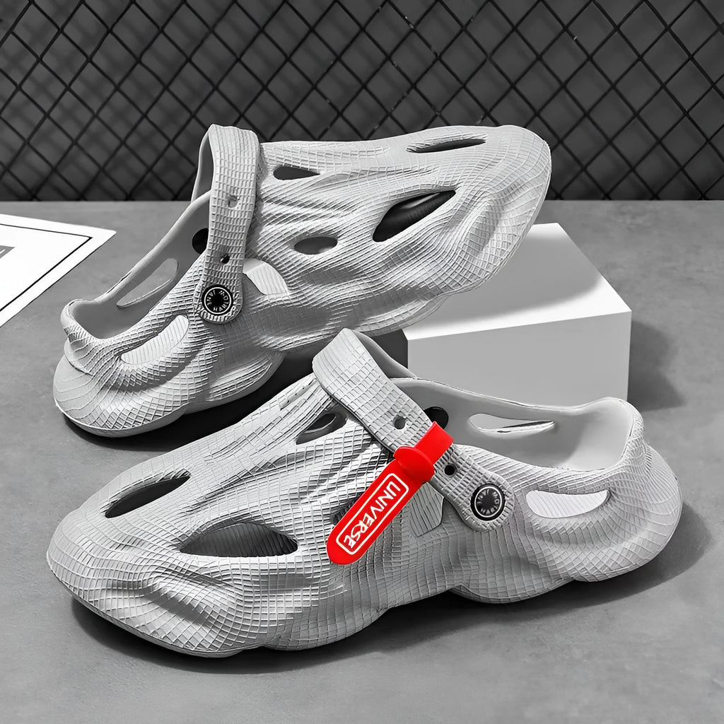 Men's grey EVA foam slippers with closed toe and thickened sole on a sandy beach.
