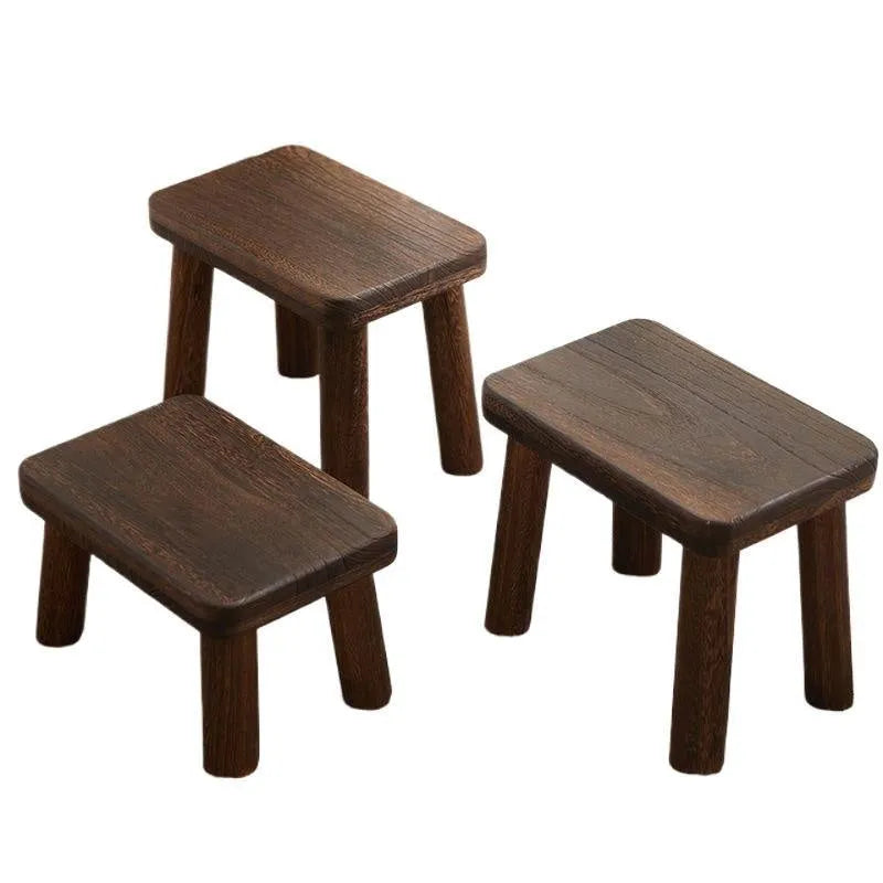 Solid wooden shoe changing stool with a distressed finish, shown in a living room setting.