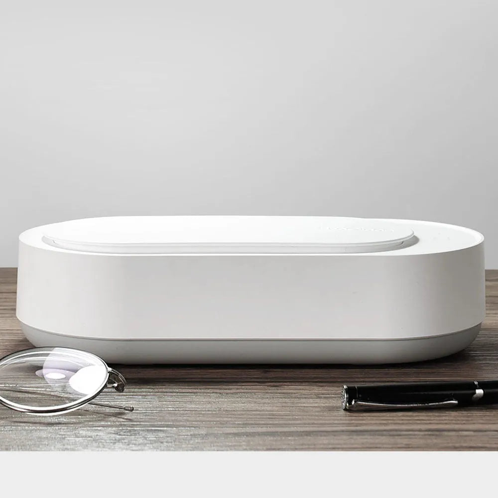 White portable ultrasonic cleaner with stainless steel tank and a single control button.