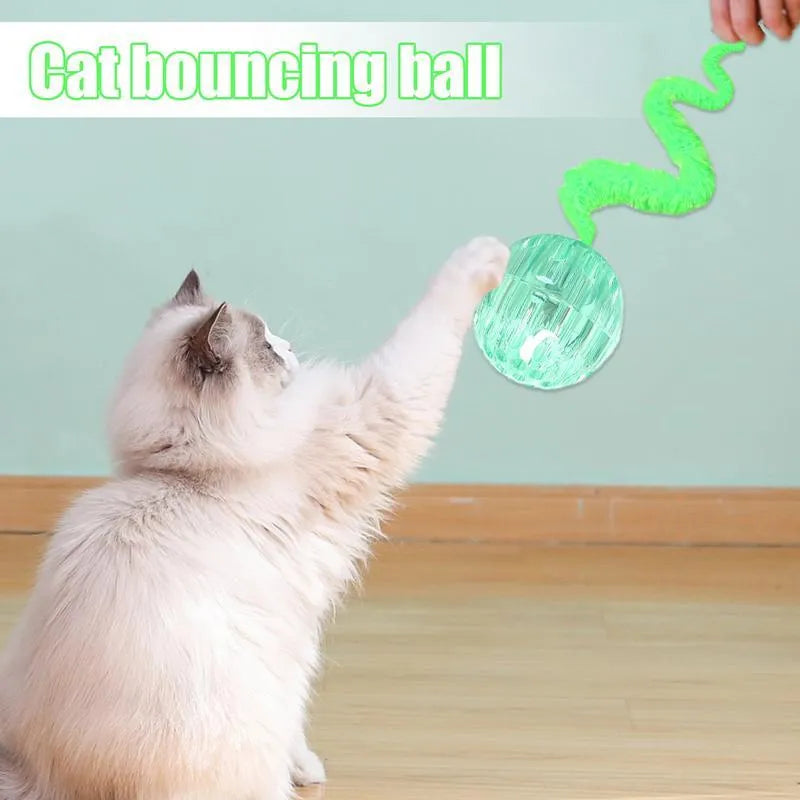 Green bouncy ball cat toy with plush tail on wooden floor