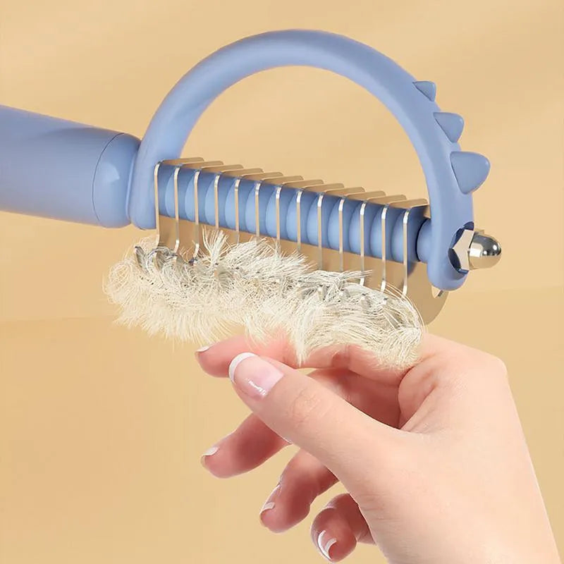 Blue dinosaur-shaped cat brush with double-sided grooming heads and self-cleaning button