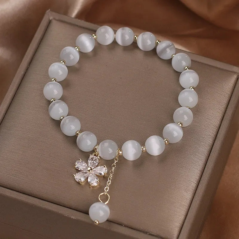 Women's single loop bracelet with white cat's eye stones and decorative tassel featuring morganite safety buckle