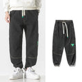 Men's loose-fit tapered cotton trousers showing tapered leg and mid-waist design in black colour