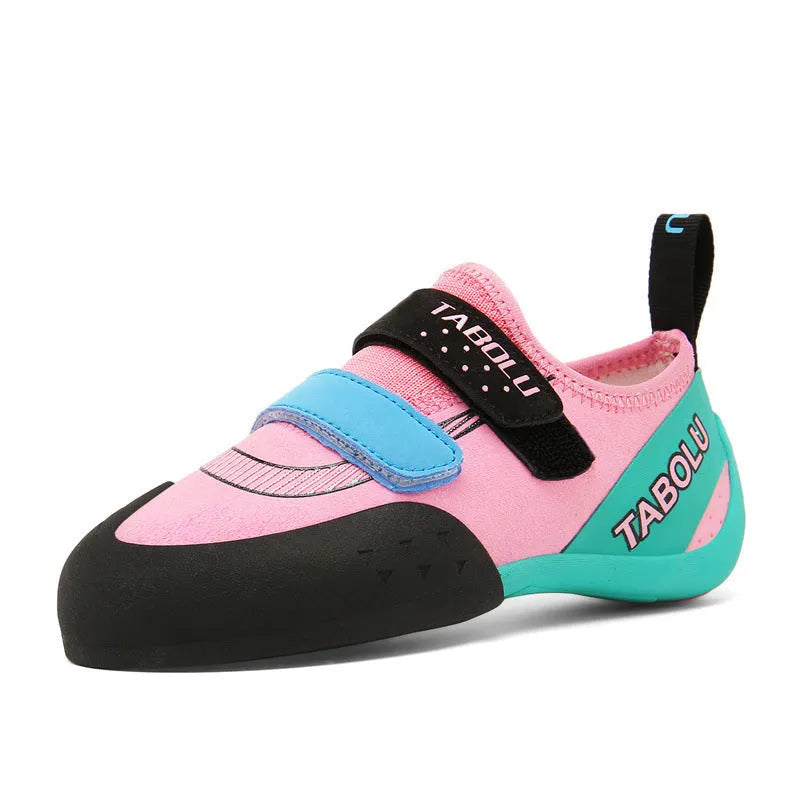 Black and red beginner rock climbing shoes with velcro strap and rubber sole on a climbing hold.