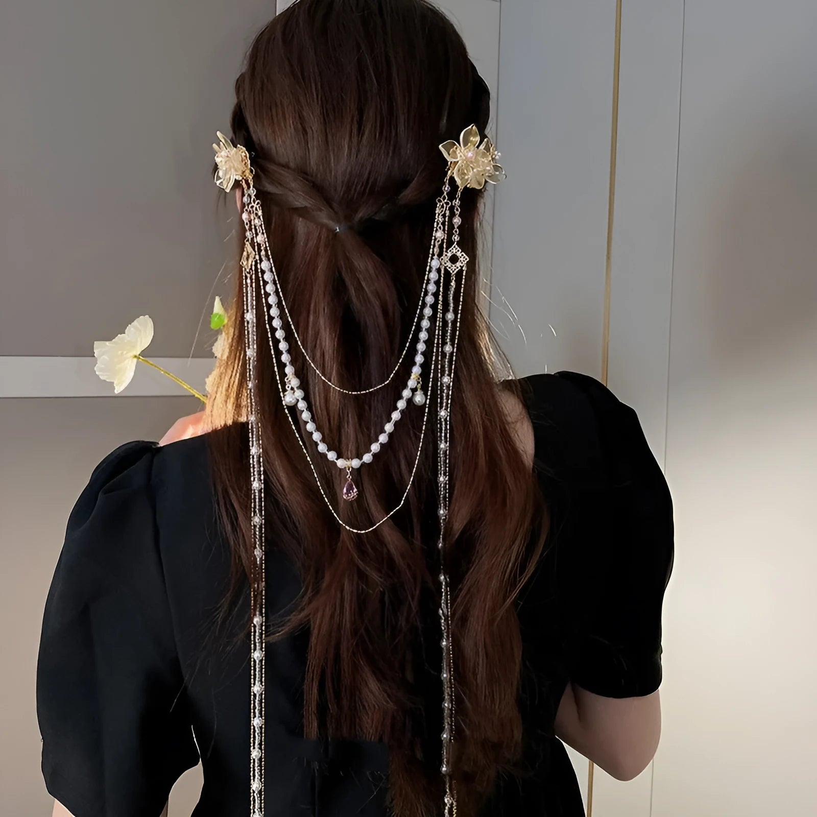 Close-up of a women's floral hairpin with white pearl, clear diamond accents, and a long gold tassel.