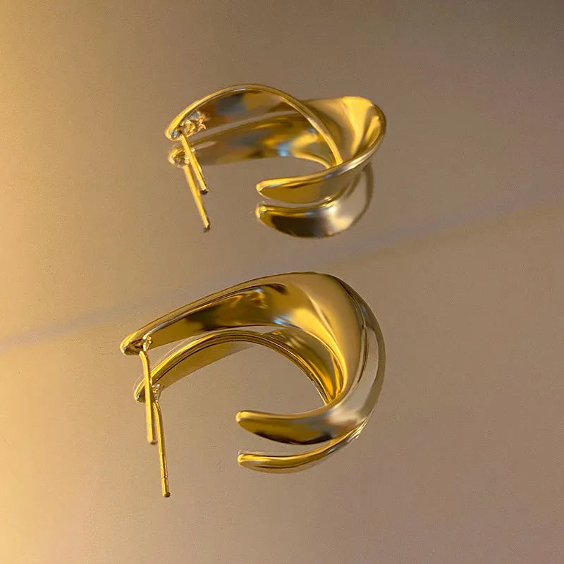 A pair of geometric round earrings with a twisted metal design in a gold electroplated finish.
