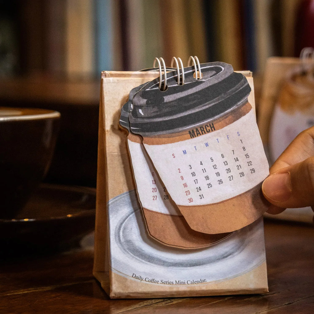 Mini coffee desk calendar 2025 with four design options on small desk surface