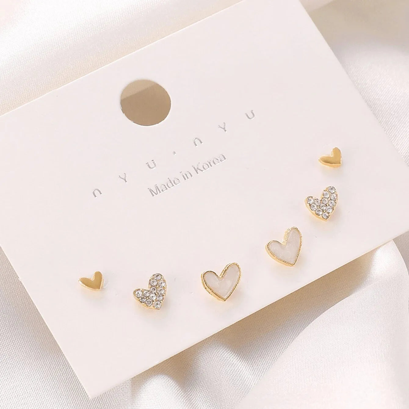 Three pairs of heart-shaped alloy earrings with electroplated finish in gold, black, and pink colours
