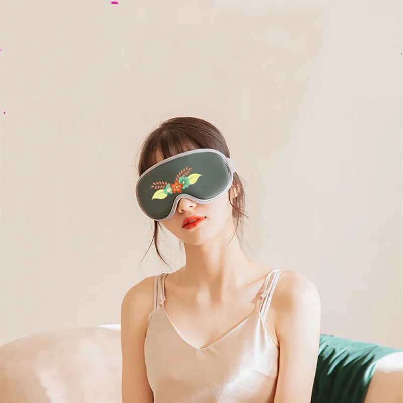 Pink or green portable steam sleep massage goggles with USB cable on a grey background.