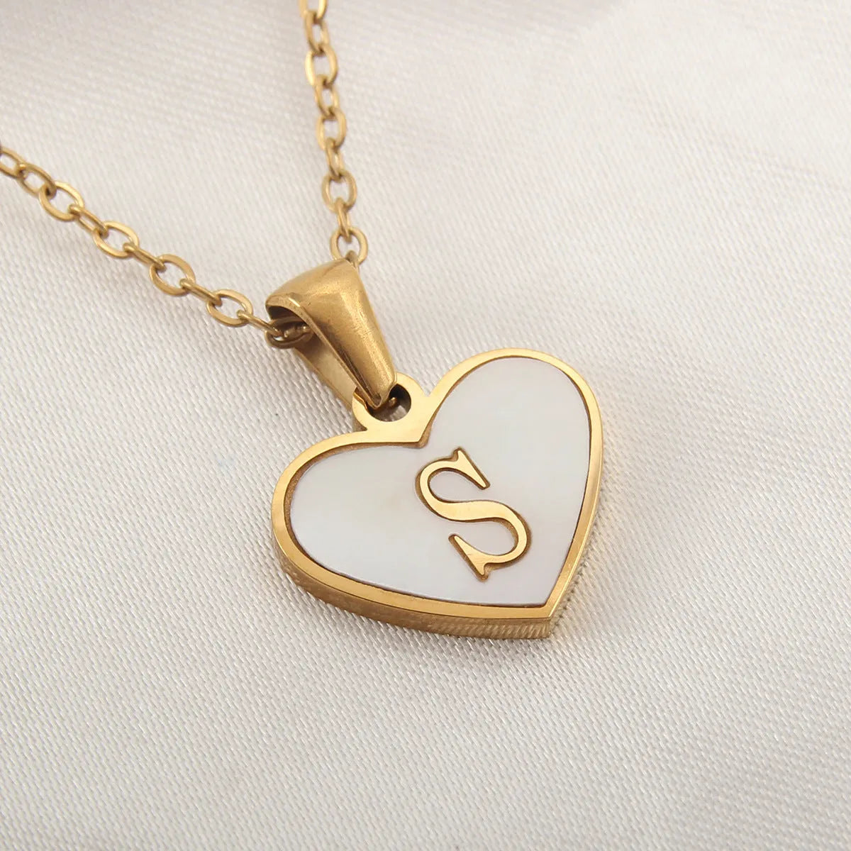 Gold-plated heart necklace with white shell pendant showing initial engraving on stainless steel chain