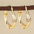 Pair of golden geometric copper earrings with ring and line design details.