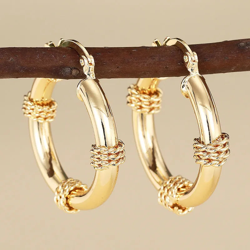 Pair of golden geometric copper earrings with ring and line design details.