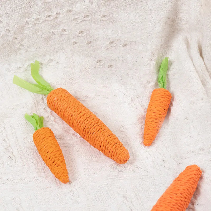 Assortment of colourful interactive cat toys including plastic carrots, ringing stones, fabric sticks, paper toys, and chewing sticks.