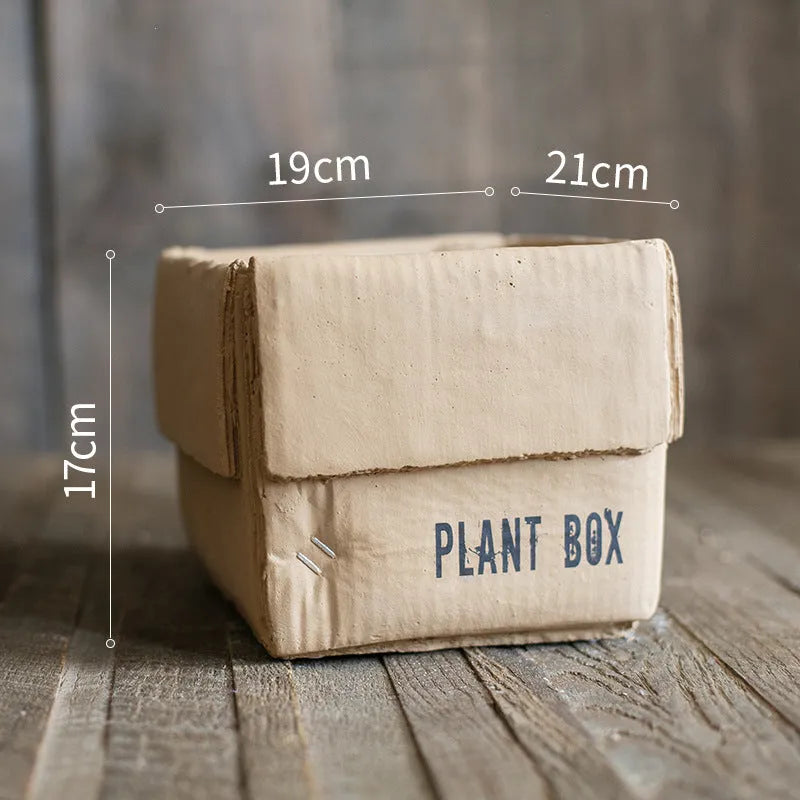 Cement flowerpot with brown paper box texture and bottom drainage holes on a floor.