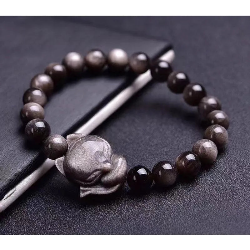 Close-up of black obsidian fox charm bracelet with 8mm polished bead on adjustable cord.