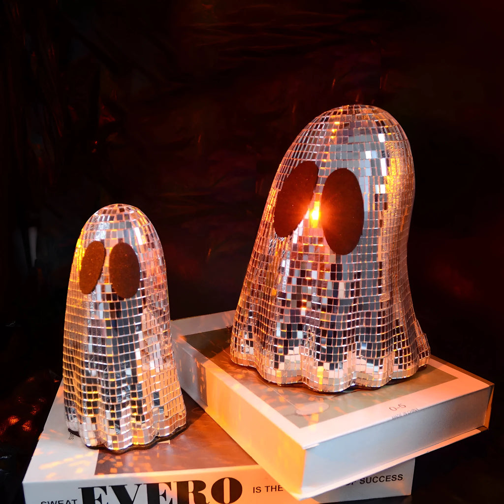 Silver glass Halloween ghost ornament with mosaic inlaid surface on a desktop.