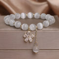 Women's single loop bracelet with white cat's eye stones and decorative tassel featuring morganite safety buckle
